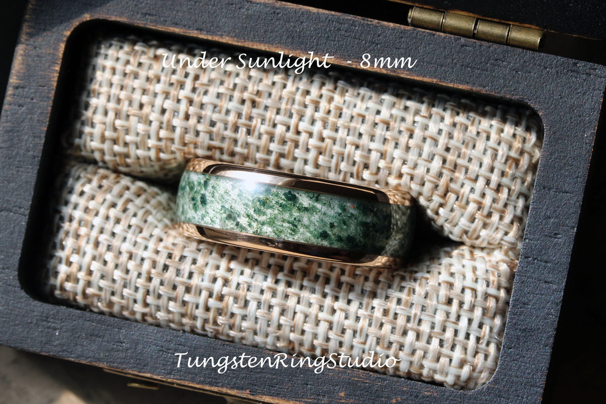 May include: A green and rose gold tungsten ring with a unique marbled pattern. The ring is 8mm wide and is displayed in a wooden box with a fabric lining. "Under Sunlight - 8mm" and "TungstenRingStudio" are printed on the box.