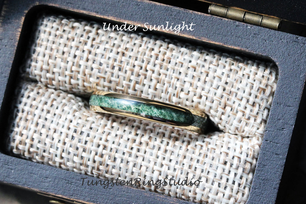 May include: A gold tungsten ring with a green stone inlay. The ring is in a small wooden box with a brown fabric lining. The text "Under Sunlight" is printed on the box. The text "TungstenRingstudio" is printed on the bottom of the box.