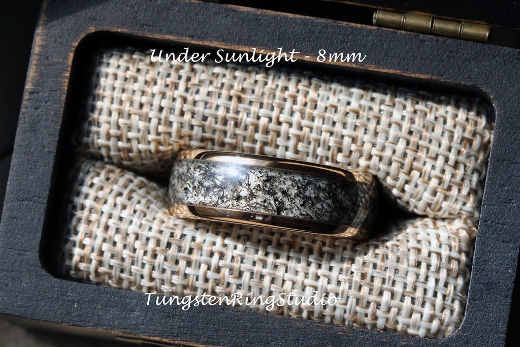 May include: A tungsten ring with a black and white speckled design, set in a black ring box with a tan fabric lining. The ring is 8mm wide and is shown under sunlight. The text "Under Sunlight - 8mm" and "TungstenRingStudio" are visible in the image.