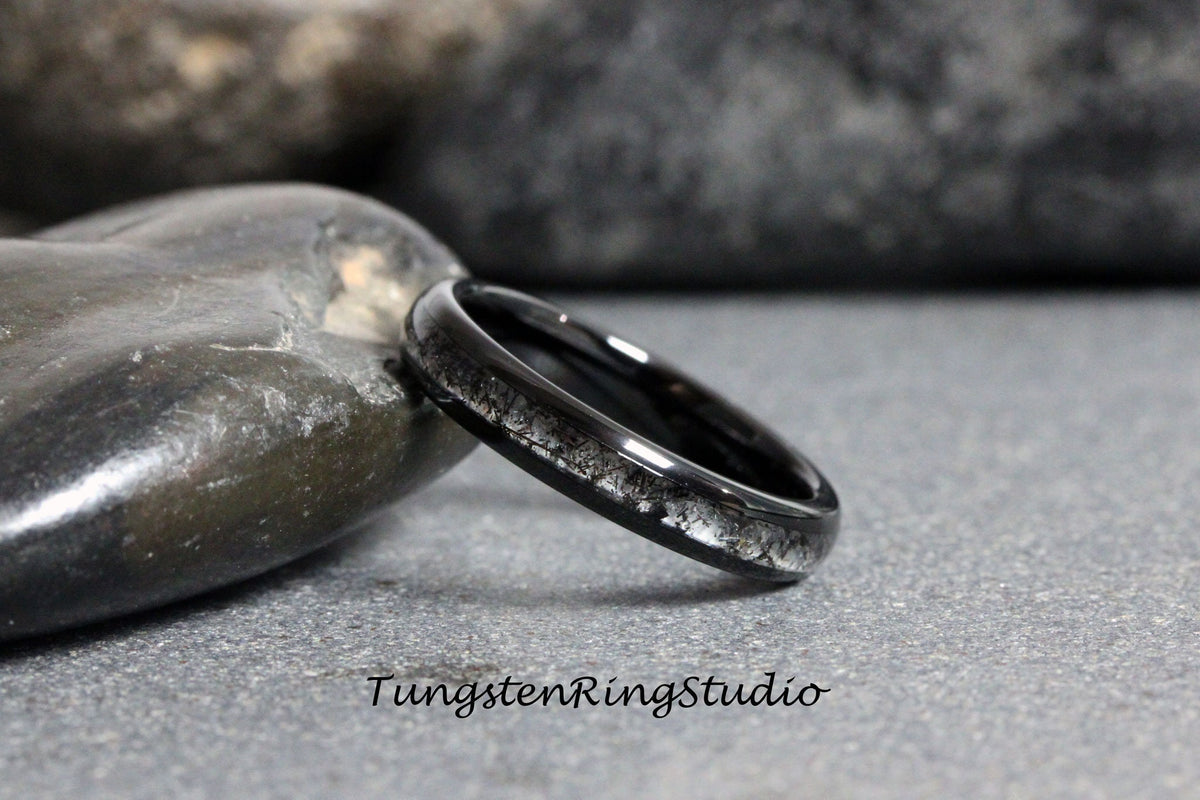 May include: A black tungsten carbide ring with a silver inlay. The ring is on a gray background.