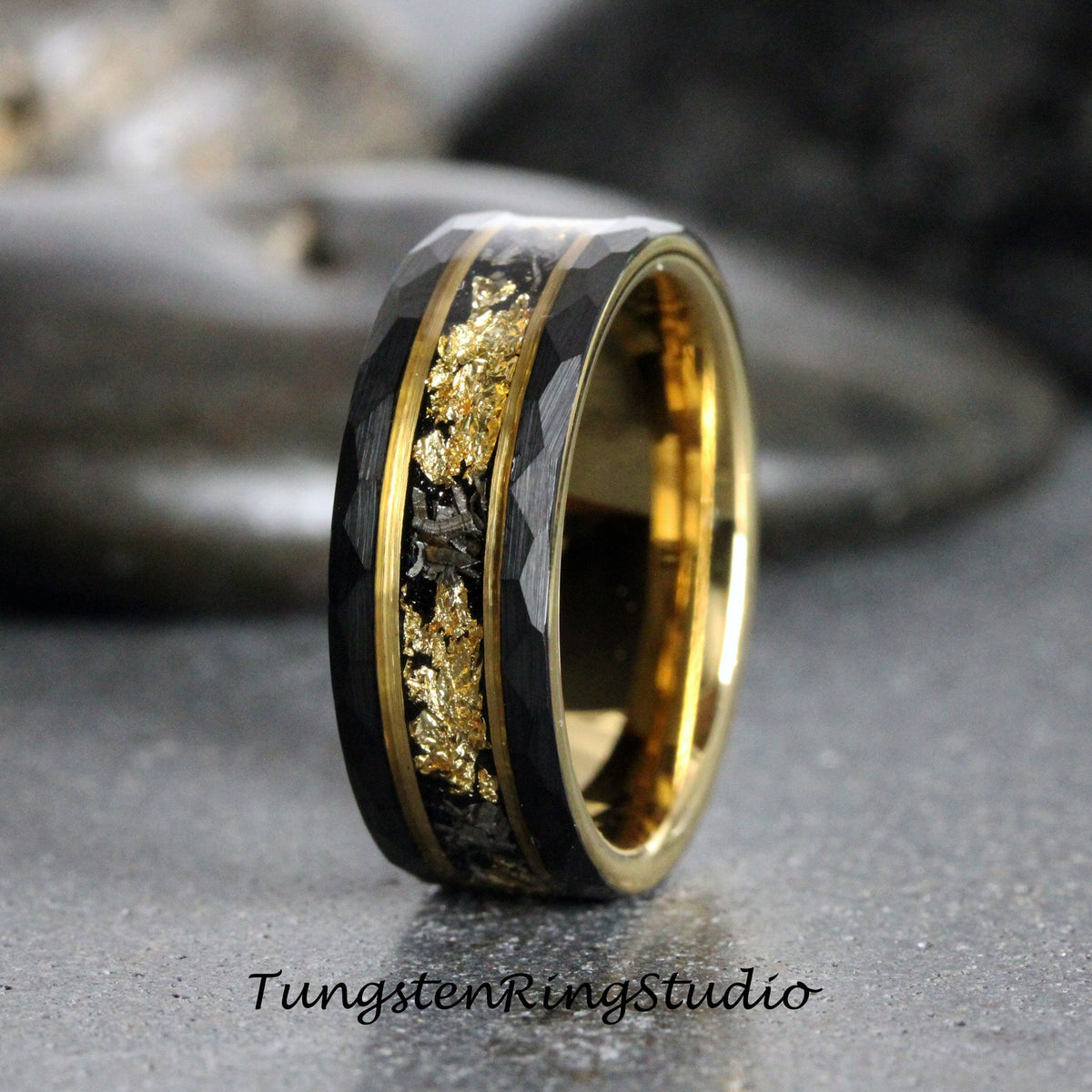 May include: A black tungsten carbide ring with a gold inlay and a hammered finish. The ring has a wide band and a flat top.