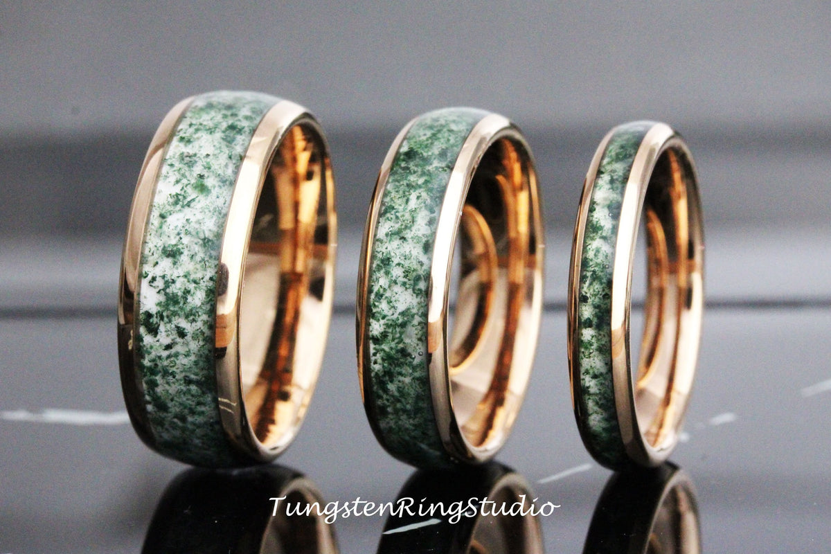 May include: Three tungsten carbide rings with a green and white inlay and a rose gold band. The rings are different sizes.