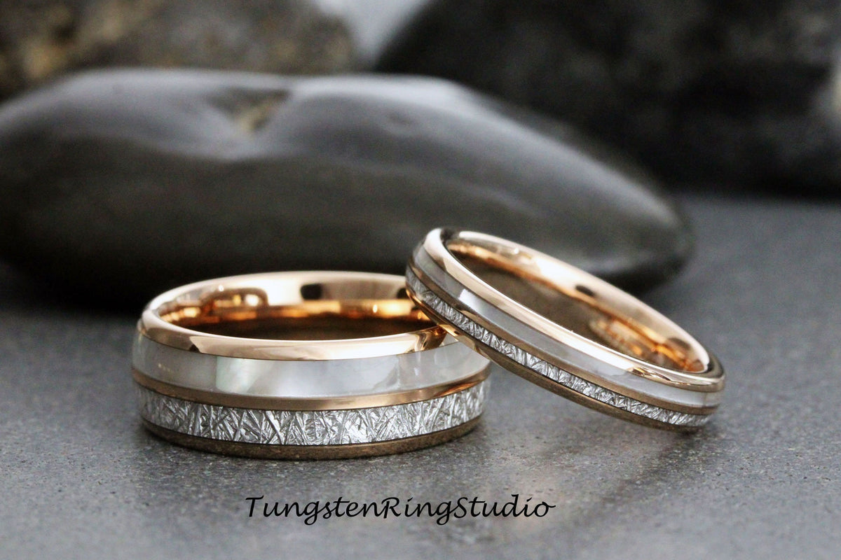 May include: Two matching tungsten wedding bands with a rose gold inlay and a white mother of pearl inlay. The bands have a hammered finish.