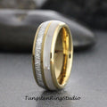 May include: A gold and silver tungsten carbide ring with a white inlay. The ring has a brushed finish and a beveled edge.