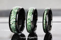 May include: Three black tungsten carbide rings with a green inlay. The rings are different sizes.
