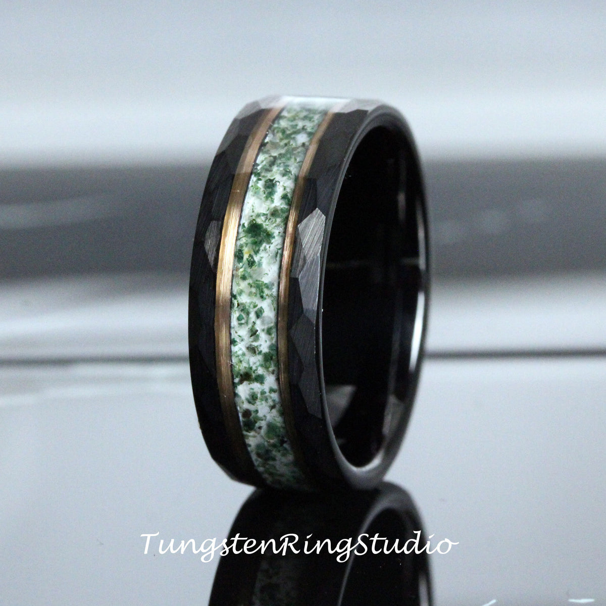 May include: A black tungsten ring with a green and white inlay and a gold band. The ring has a hammered finish.