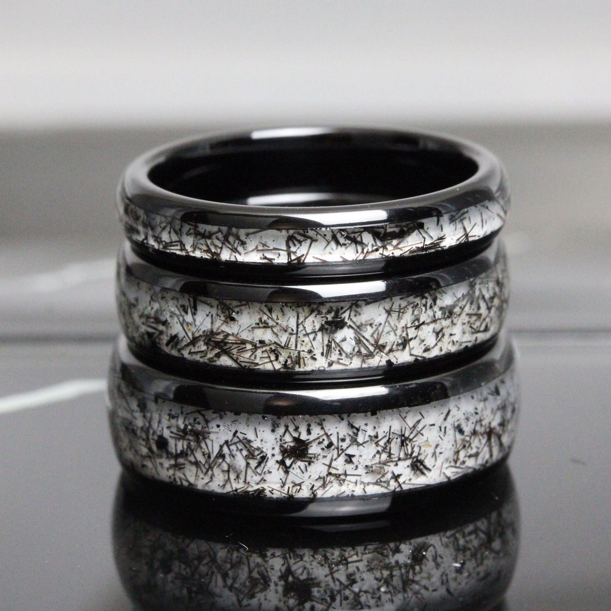 May include: Three black ceramic rings with a white speckled pattern. The rings are stacked on top of each other.