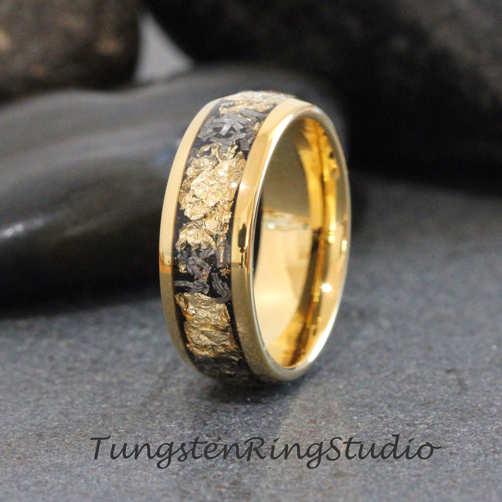 May include: A gold tungsten carbide ring with a black inlay featuring gold flecks. The ring has a polished finish.