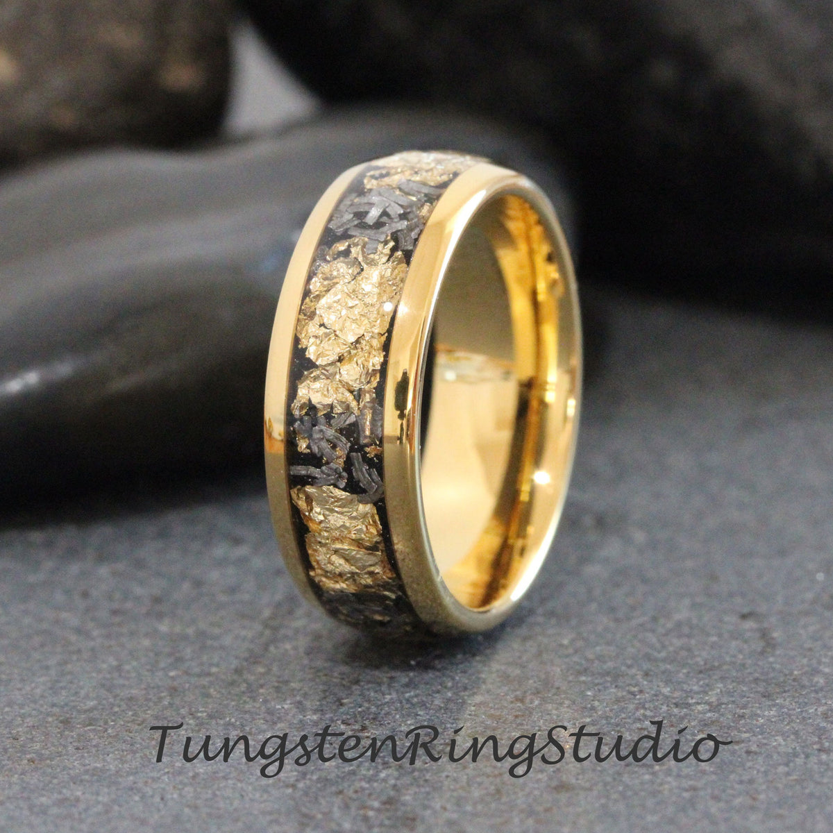 May include: A gold tungsten carbide ring with a black inlay featuring gold flecks. The ring has a polished finish.