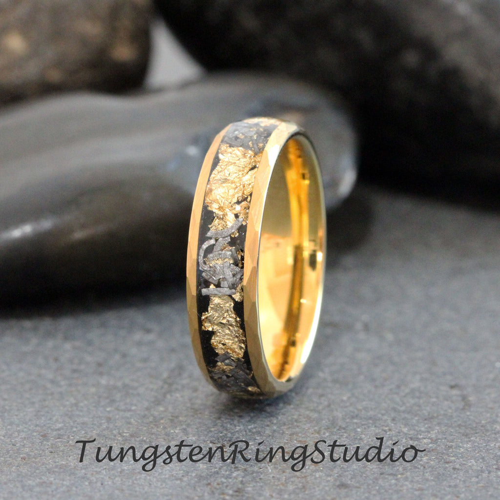May include: A gold and black tungsten ring with a band of gold and a black inlay with gold flakes. The ring is on a gray background.