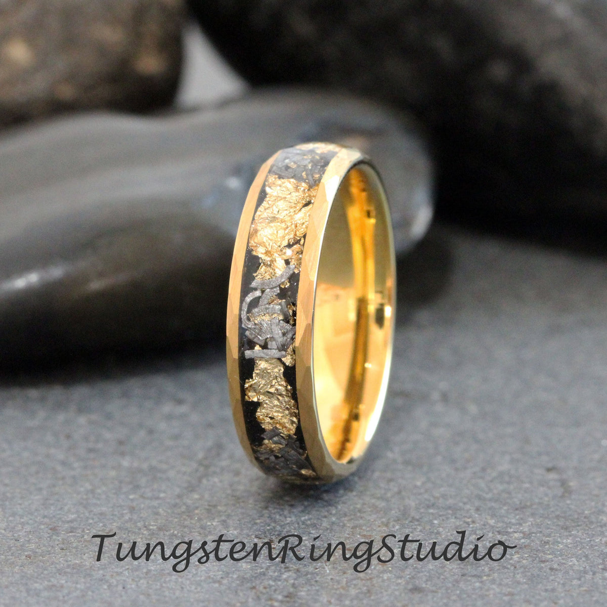 May include: A gold and black tungsten ring with a band of gold and a black inlay with gold flakes. The ring is on a gray background.