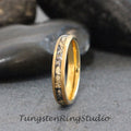 May include: A gold tungsten carbide ring with a black and gold inlay. The ring has a beveled edge and a polished finish.