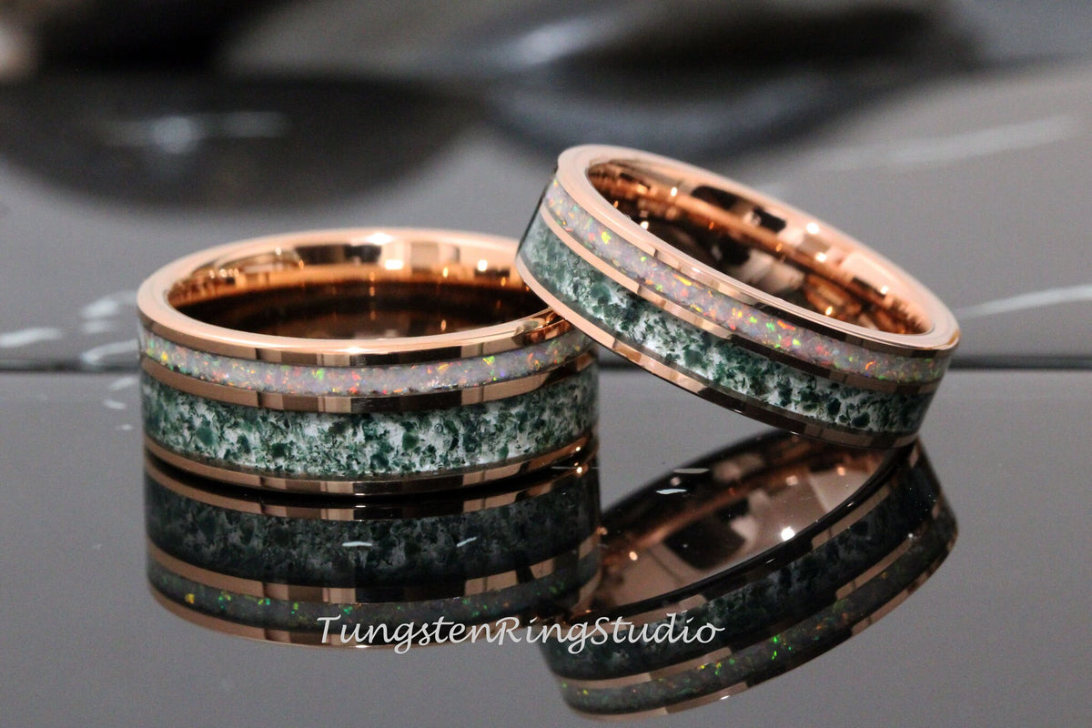May include: Two tungsten carbide rings with a rose gold finish. The rings have a green and white inlay with a speckled pattern. The rings are stacked on top of each other.