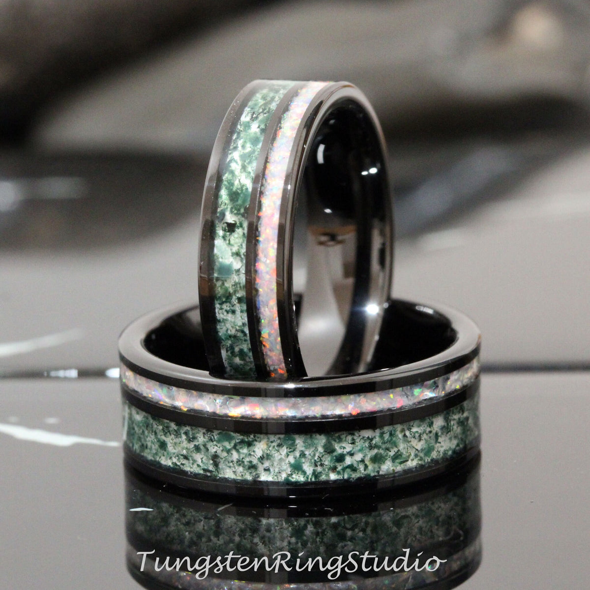 May include: Two black tungsten carbide rings with green and white inlay. The rings are stacked on top of each other.