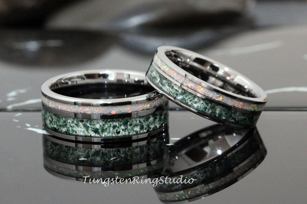 May include: Two silver tungsten carbide rings with green and white opal inlay. The rings are stacked on top of each other.