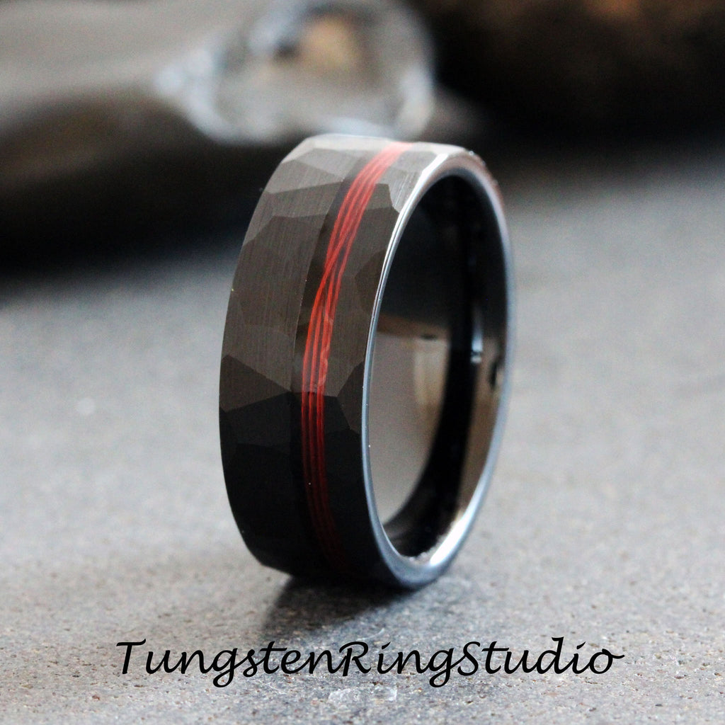 May include: Black tungsten carbide ring with a hammered finish and a red inlay. The ring is approximately 8mm wide.