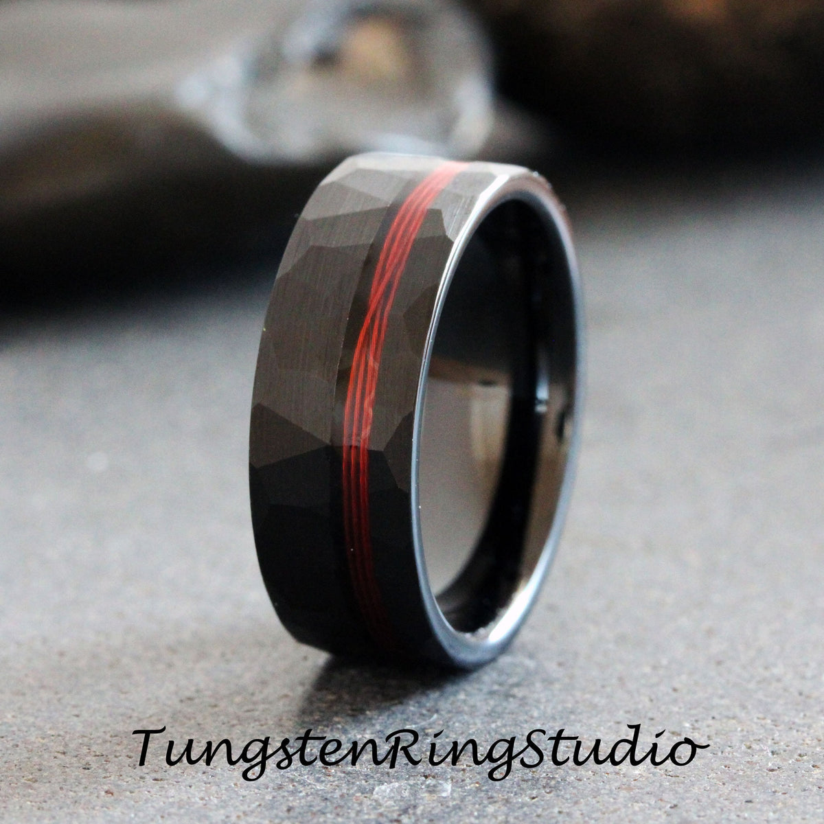 May include: Black tungsten carbide ring with a hammered finish and a red inlay. The ring is approximately 8mm wide.