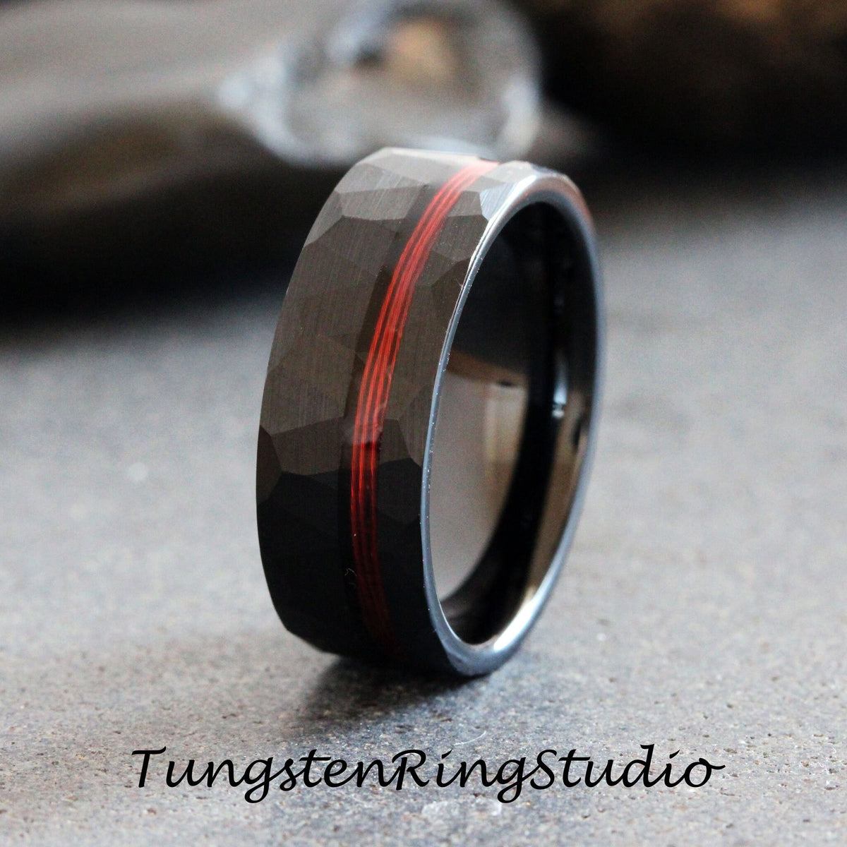 May include: A black tungsten ring with a hammered finish and a red inlay. The ring is a popular choice for men's wedding bands.