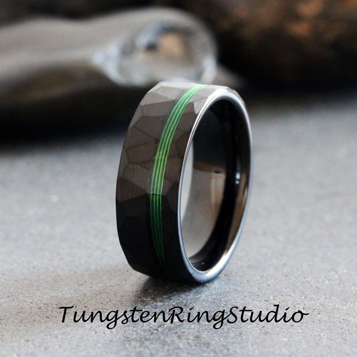 May include: A black tungsten ring with a hammered finish and three green lines around the band.