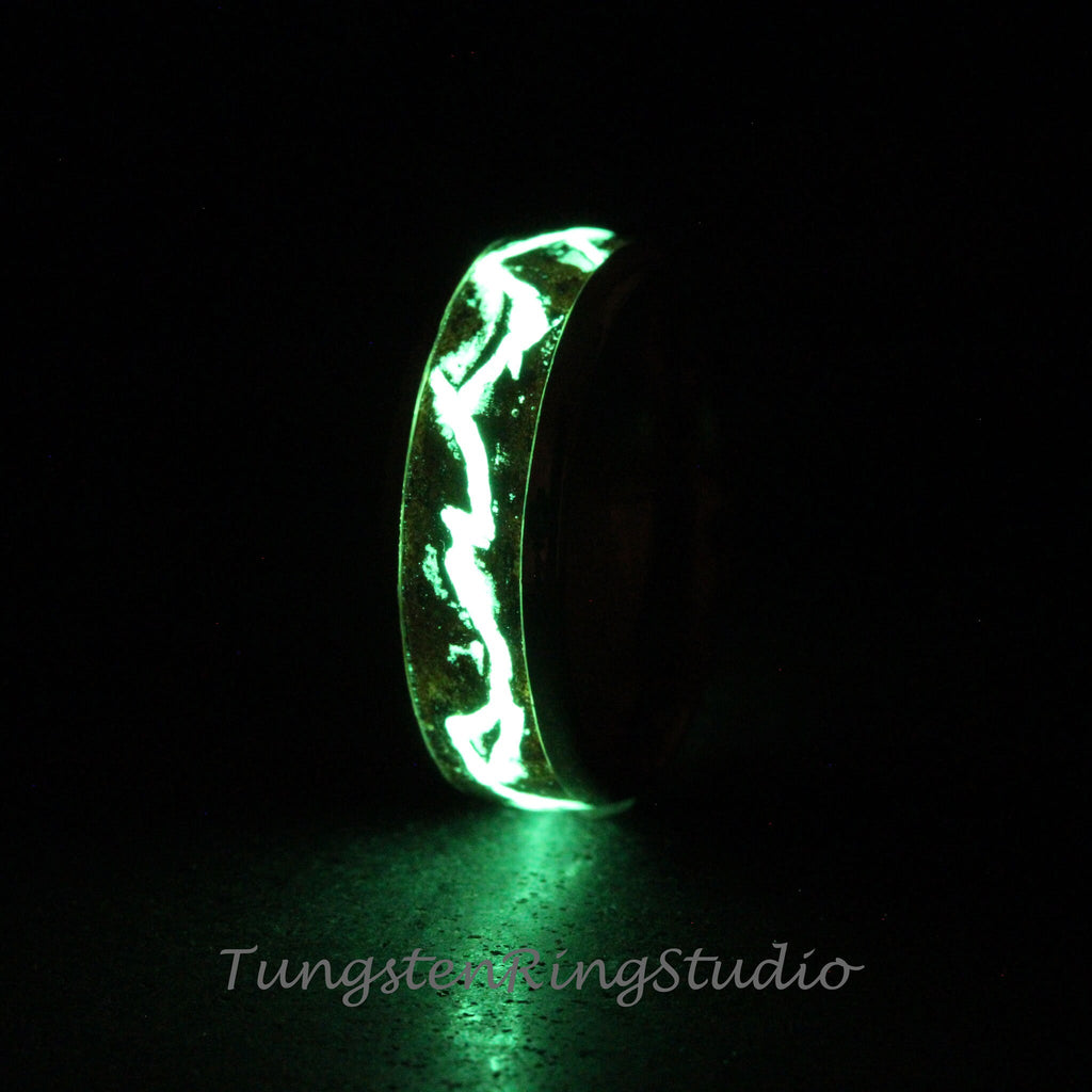May include: A black tungsten ring with a green glow-in-the-dark inlay. The inlay has a swirling pattern.