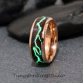 May include: A rose gold tungsten carbide ring with a dark brown wood inlay and a green glow-in-the-dark design. The ring is a men's wedding band.