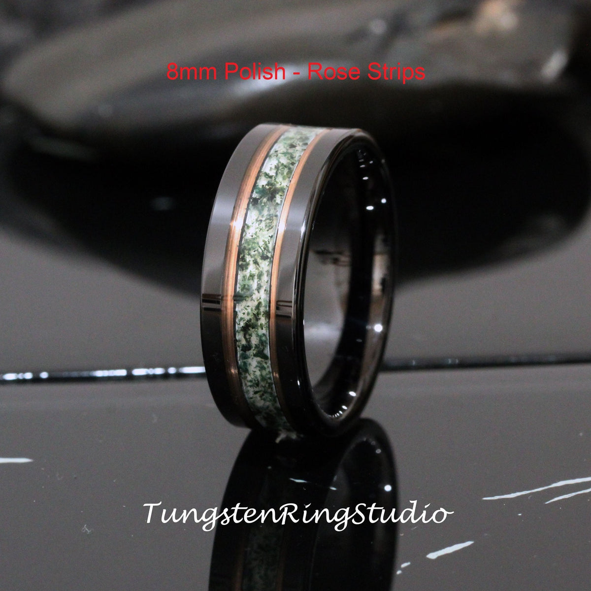 May include: A black tungsten carbide ring with a green and rose gold inlay. The ring is 8mm wide and has a polished finish. The text "8mm Polish - Rose Strips" is visible in the image.