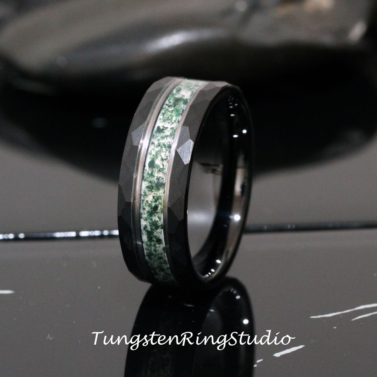 May include: A black tungsten carbide ring with a green and white inlay. The ring has a beveled edge and a brushed finish.
