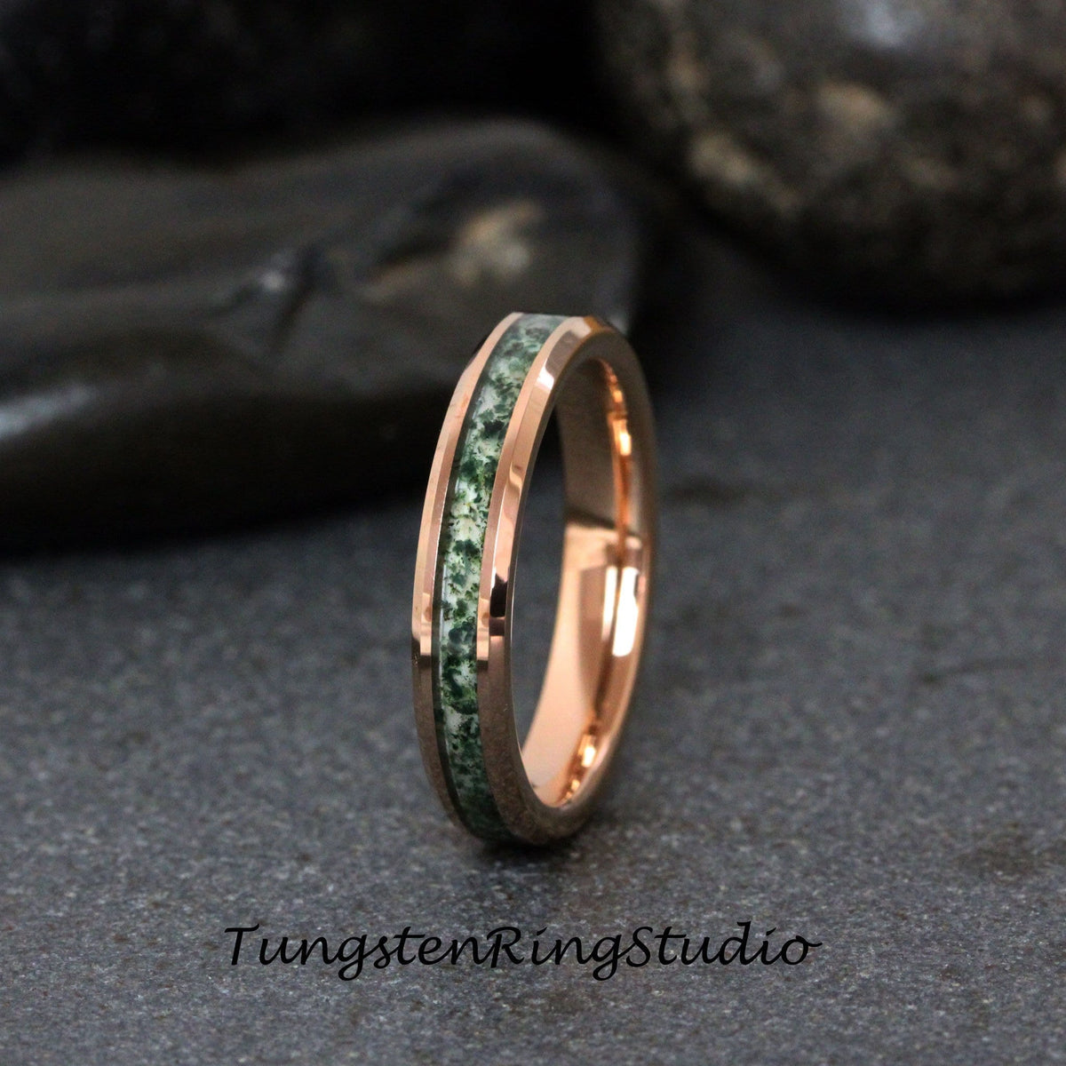 May include: A rose gold tungsten carbide ring with a green and white inlay. The ring is a simple band with a beveled edge.