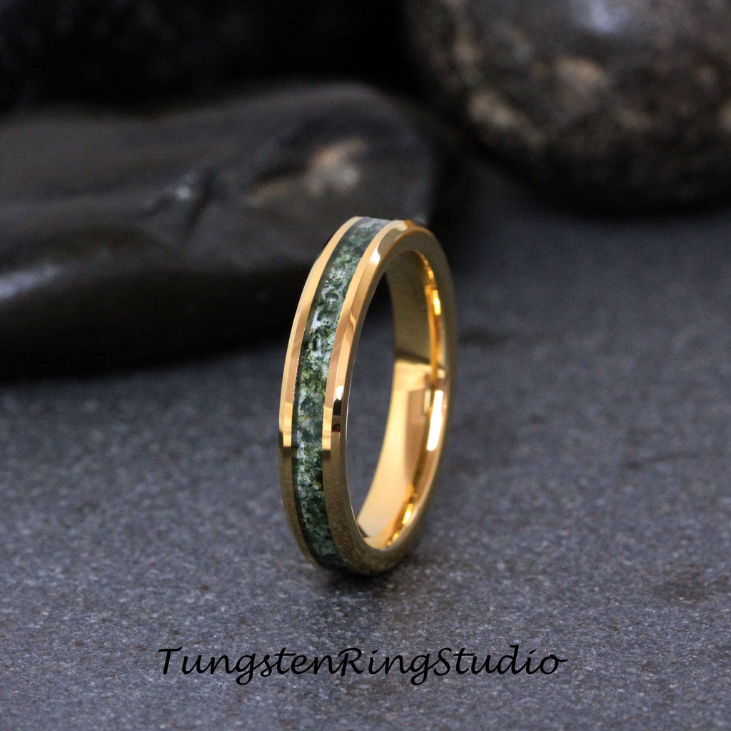 May include: A gold tungsten carbide ring with a green inlay. The ring is a simple band with a beveled edge.