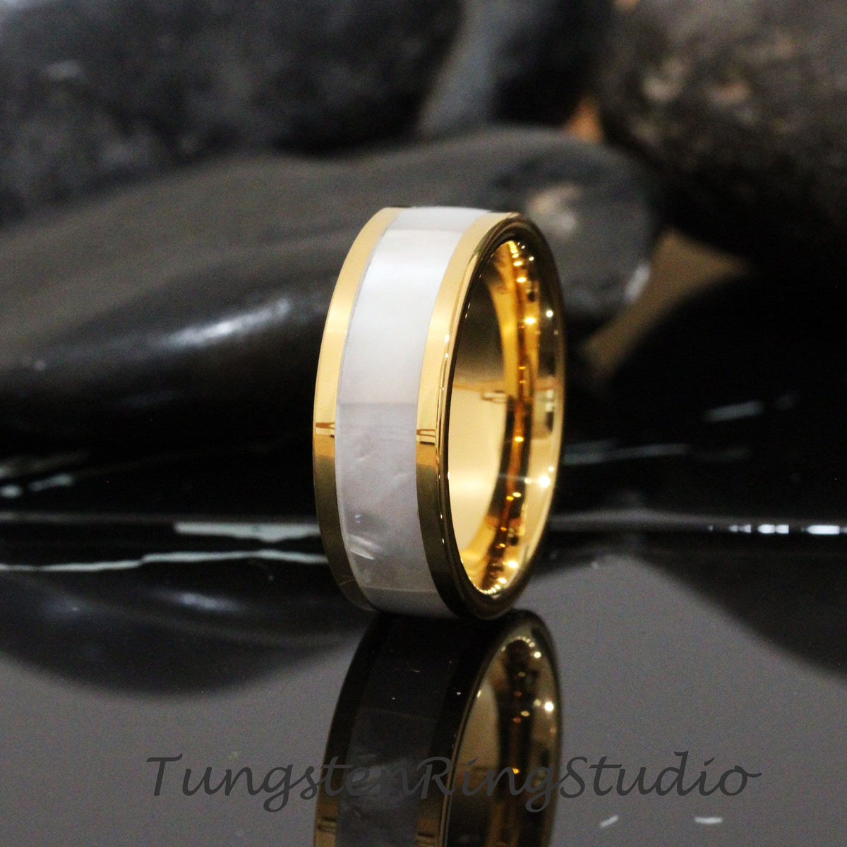 May include: A gold tungsten carbide ring with a white mother-of-pearl inlay. The ring is polished and has a beveled edge.