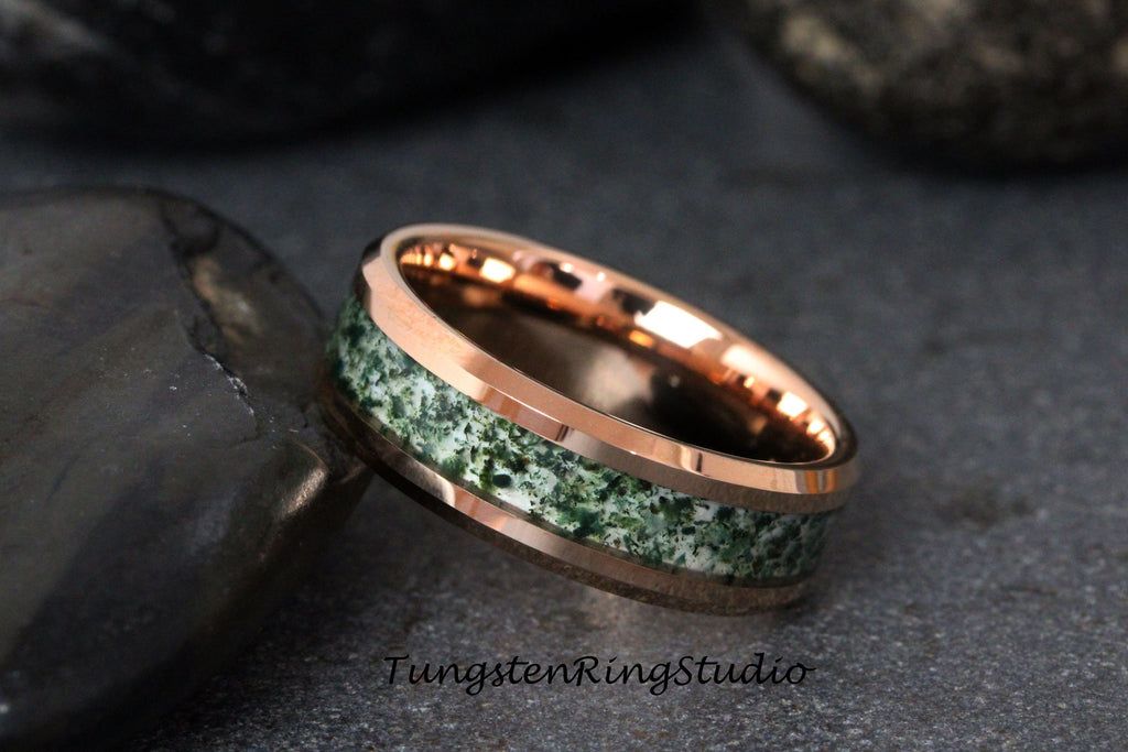 May include: A rose gold tungsten carbide ring with a green and white inlay. The ring has a beveled edge and a polished finish.