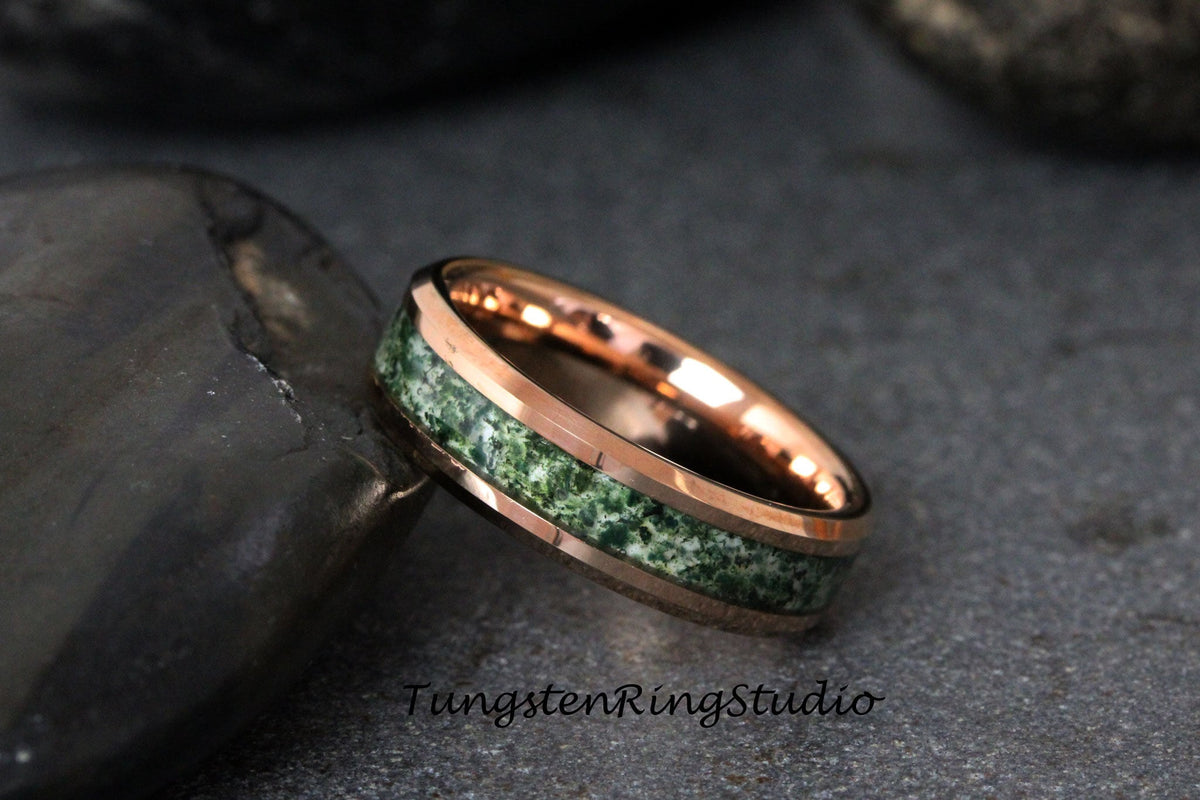 May include: A rose gold tungsten carbide ring with a green and white inlay. The ring has a beveled edge and a polished finish.