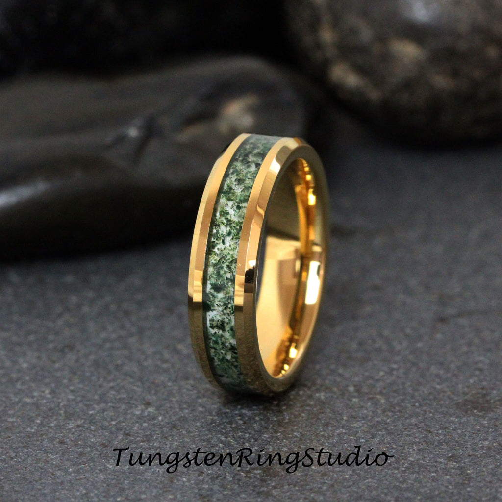 May include: A gold tungsten carbide ring with a green and white inlay. The ring has a beveled edge and a polished finish.