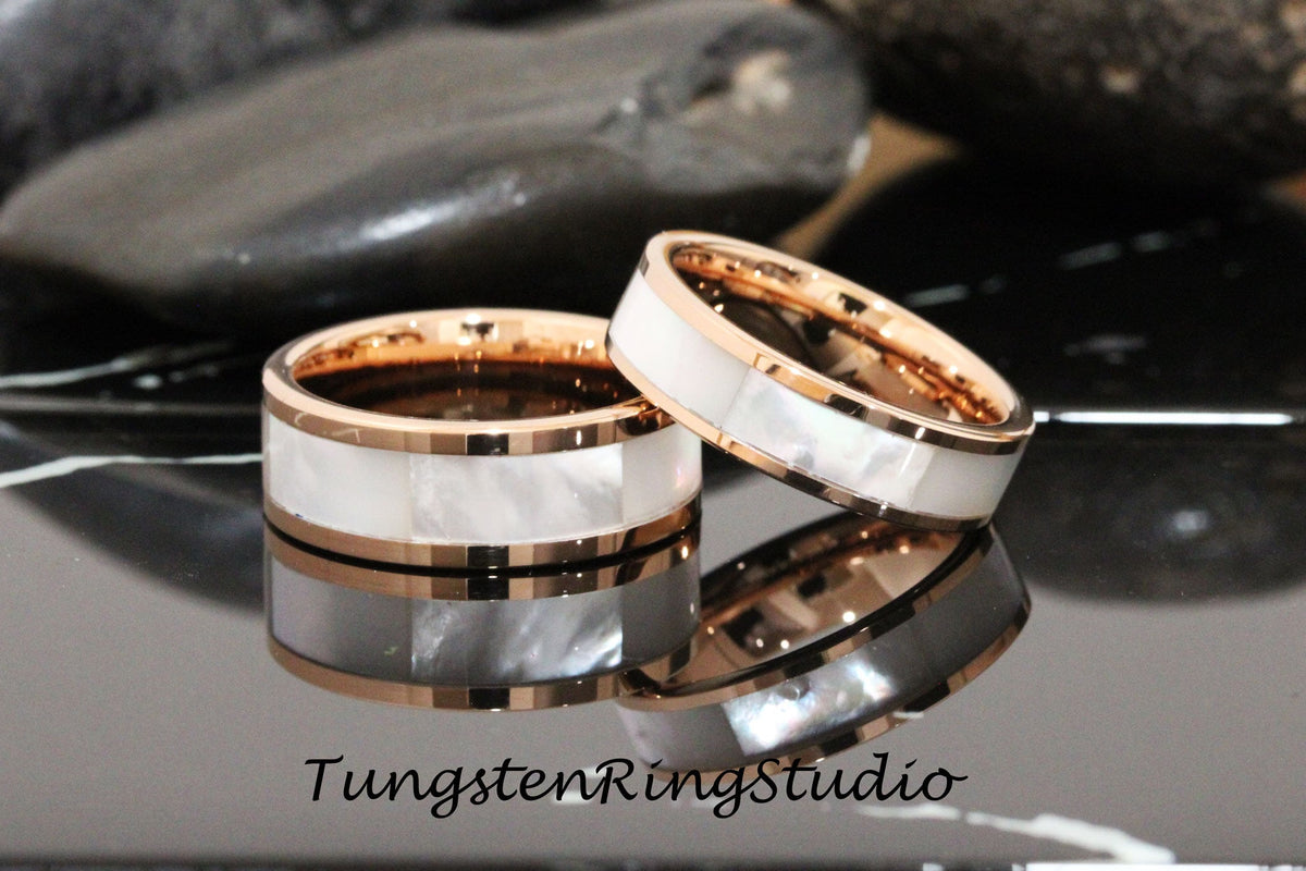 May include: Two rose gold tungsten carbide rings with a white mother of pearl inlay. The rings are stacked on top of each other. TungstenRingStudio.