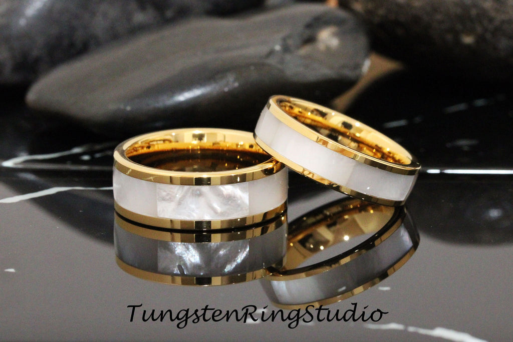 May include: Two gold tungsten carbide rings with a white mother of pearl inlay. The rings are stacked on top of each other.