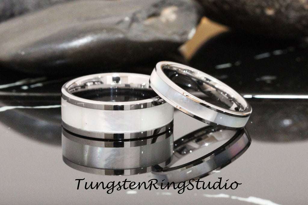 May include: Two silver tungsten carbide rings with a white mother of pearl inlay. The rings are stacked on top of each other.