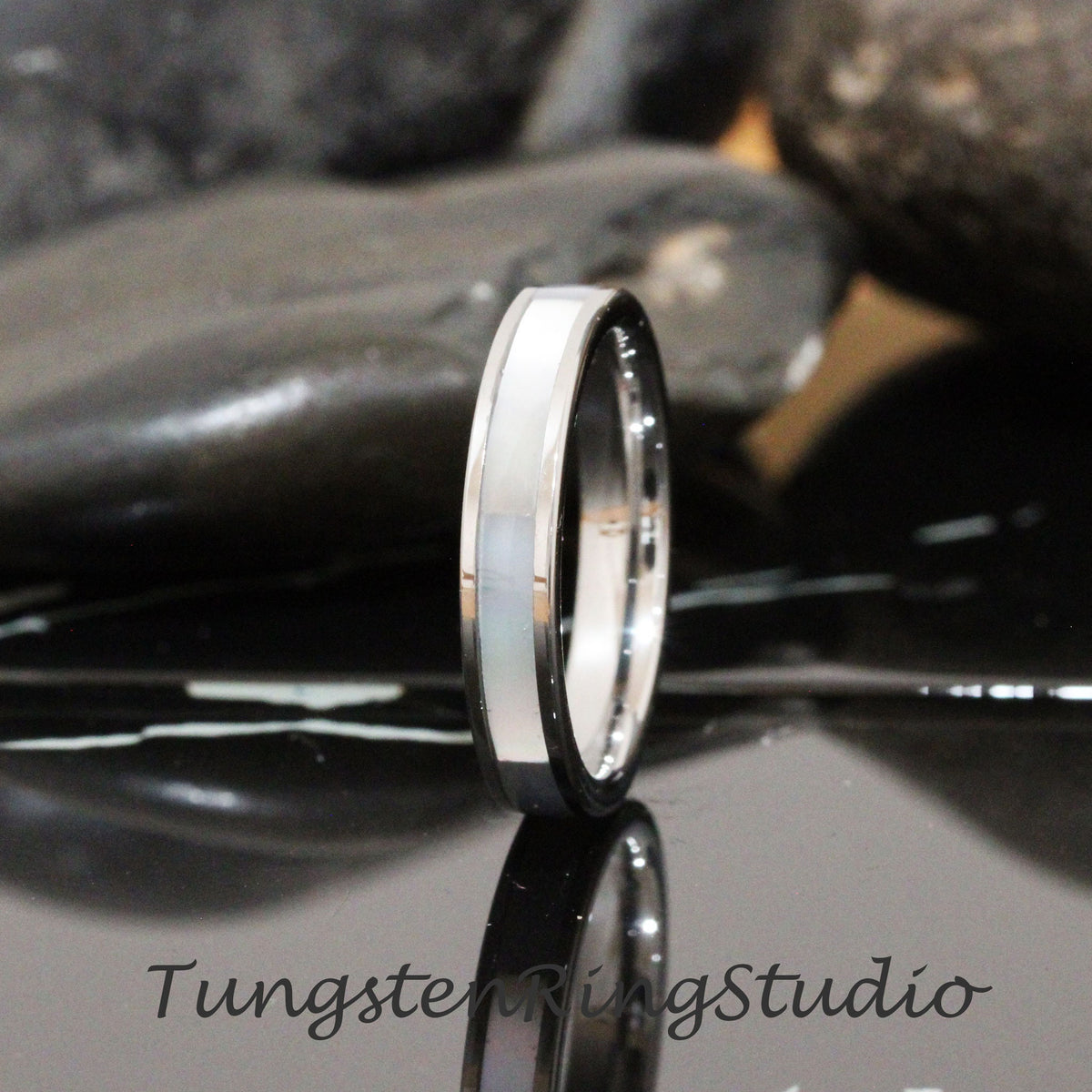 May include: A silver tungsten ring with a white inlay. The ring is polished and has a beveled edge.