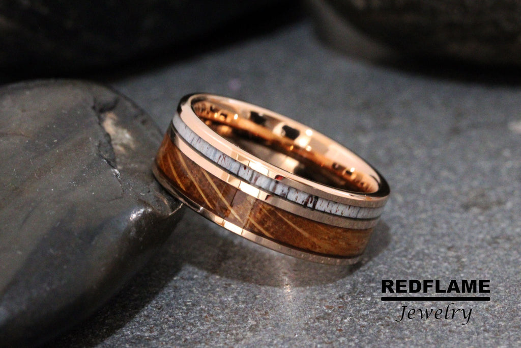 May include: A rose gold tungsten carbide ring with a brown wood inlay and white antler accents.  REDFLAME Jewelry.