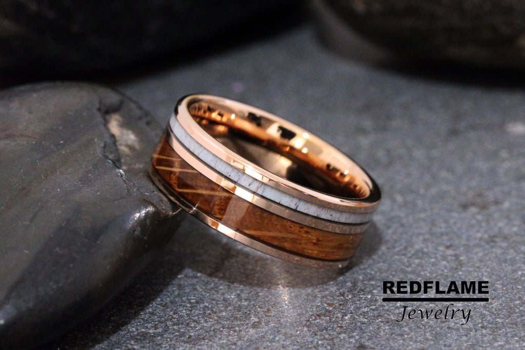 May include: A rose gold tungsten carbide ring with a brown wood inlay and white bone accents. REDFLAME Jewelry.