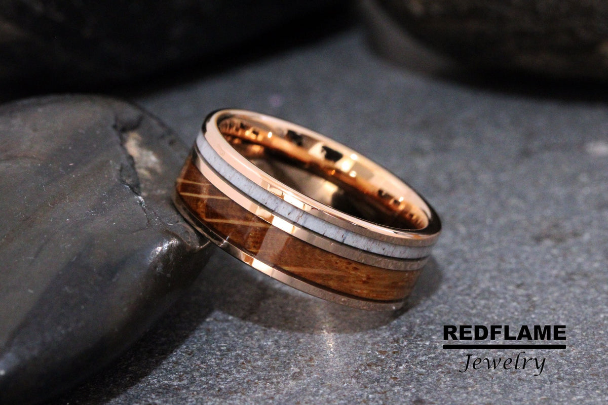 May include: A rose gold tungsten carbide ring with a brown wood inlay and white bone accents. REDFLAME Jewelry.