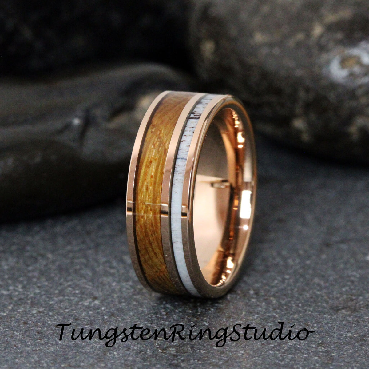 May include: A rose gold tungsten carbide ring with a brown wood inlay and white antler accents. Tungsten Ring Studio.