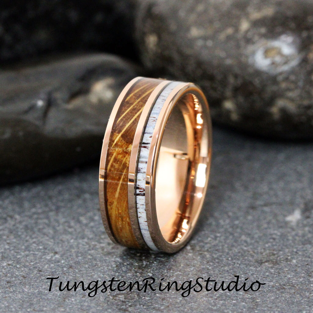 May include: A rose gold tungsten carbide ring with a brown wood inlay and a white antler inlay. The ring is 8mm wide.