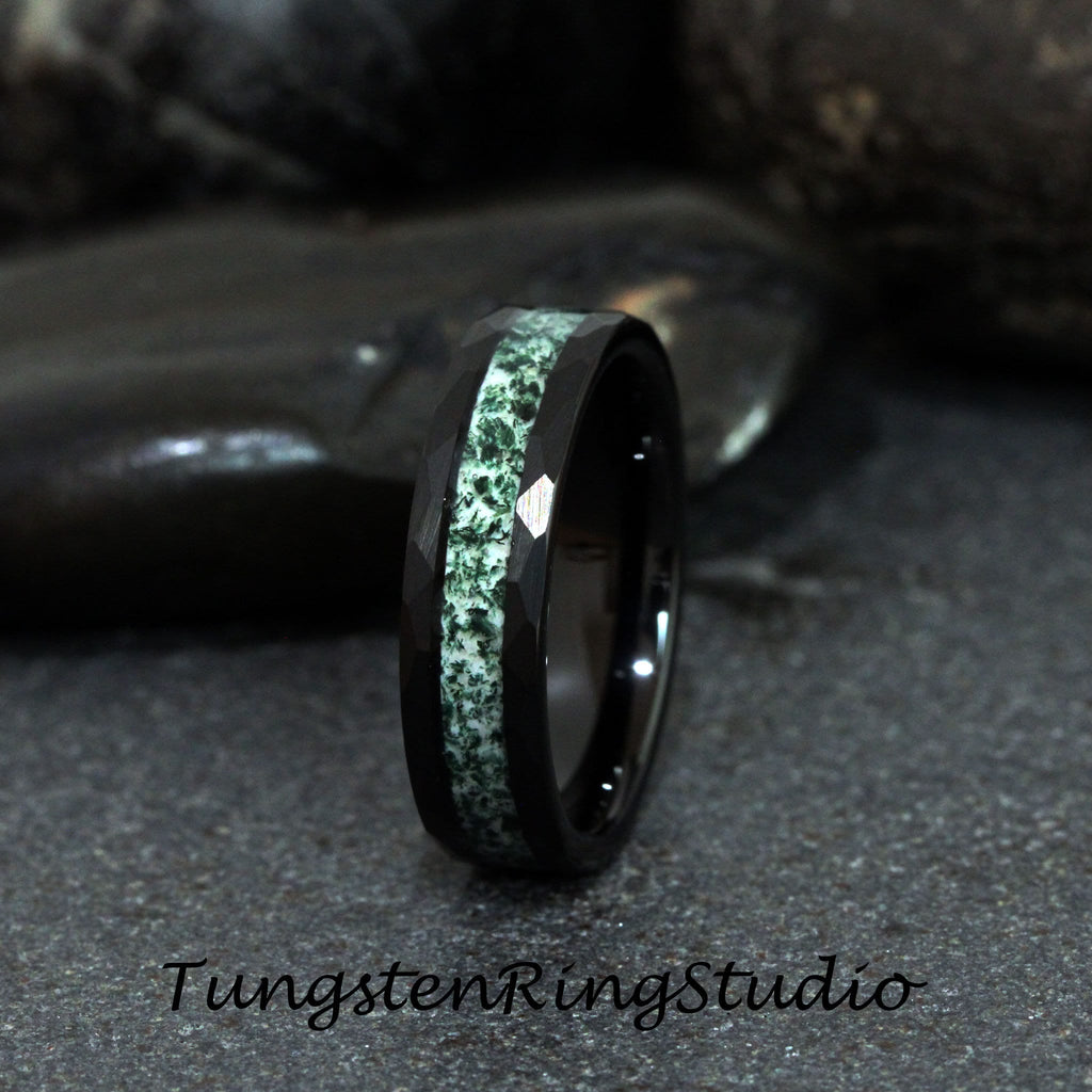 May include: A black tungsten carbide ring with a green and white inlay. The ring has a beveled edge and a polished finish.