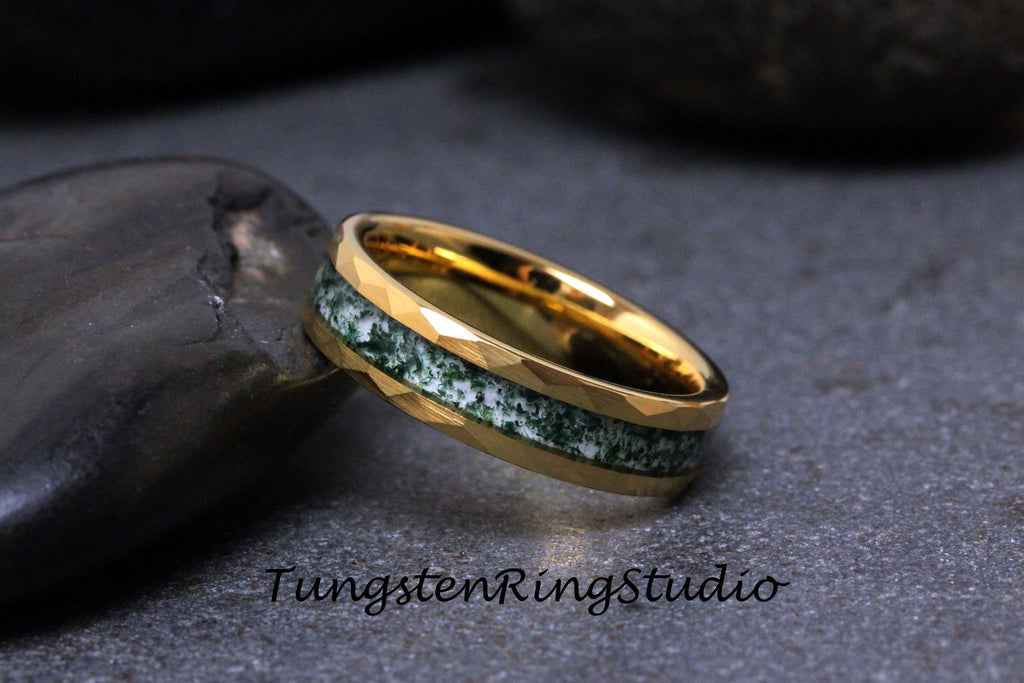 May include: A gold tungsten carbide ring with a green and white inlay. The ring has a beveled edge and is shown on a gray background.