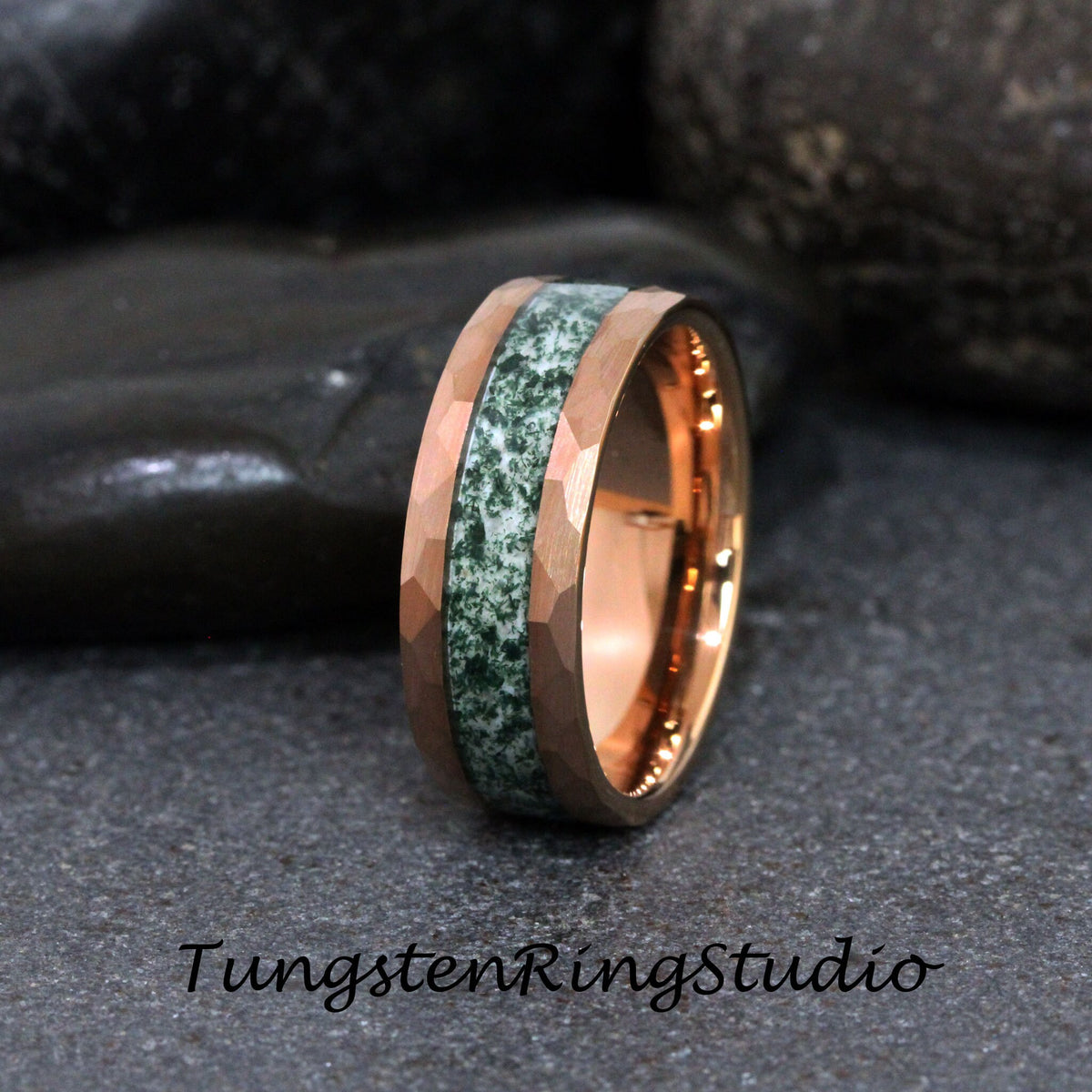 May include: Rose gold tungsten ring with a hammered finish and a green stone inlay. The ring features a central band of green stone, flanked by rose gold bands. The text "TungstenRingStudio" is at the bottom.