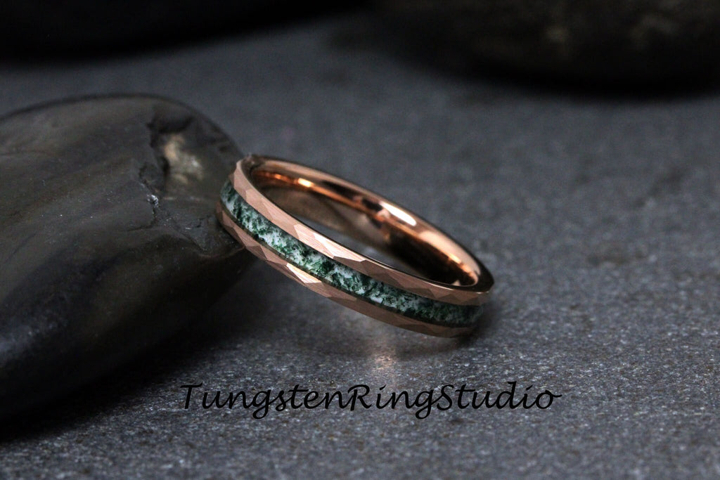 May include: Rose gold ring with a faceted band and a green stone inlay. The ring has a polished finish and is set against a dark background. The text "TungstenRingstudio" is visible.