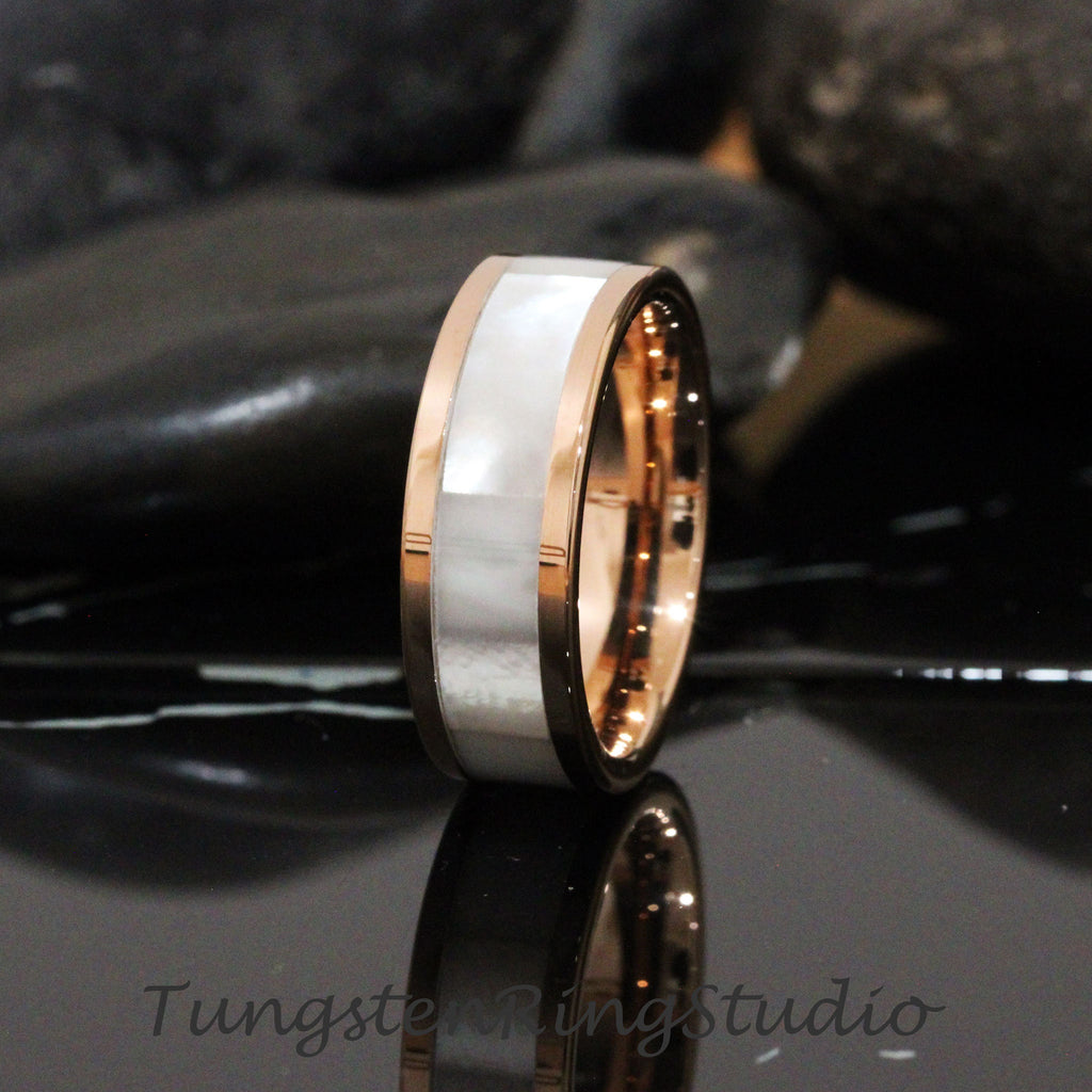 May include: A rose gold tungsten carbide ring with a white mother of pearl inlay.