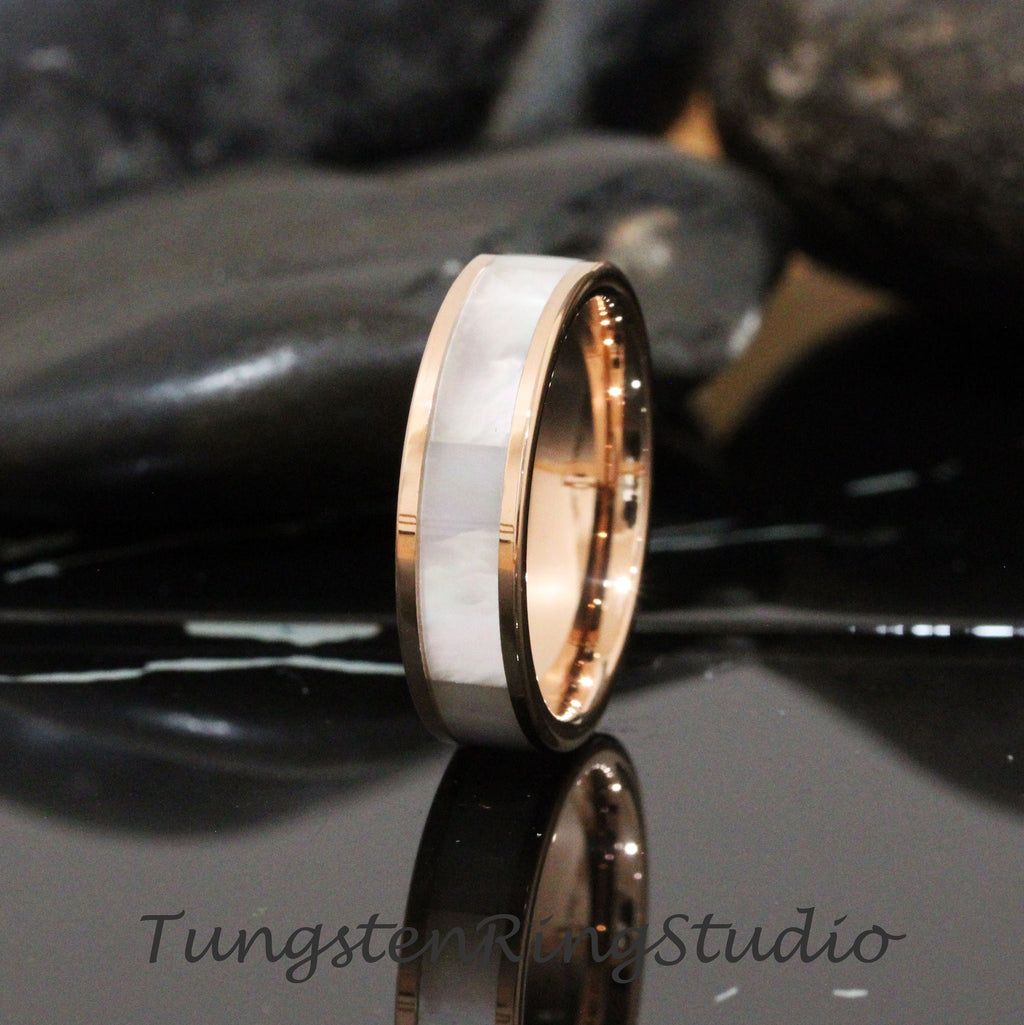 May include: A rose gold tungsten carbide ring with a white mother-of-pearl inlay. The ring is 8mm wide and has a polished finish.