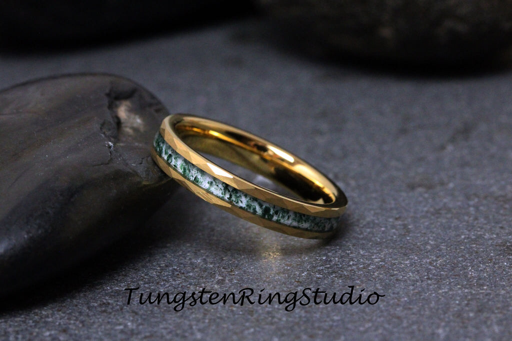 May include: A gold tungsten carbide ring with a green and white inlay. The ring has a beveled edge and is shown on a gray background.