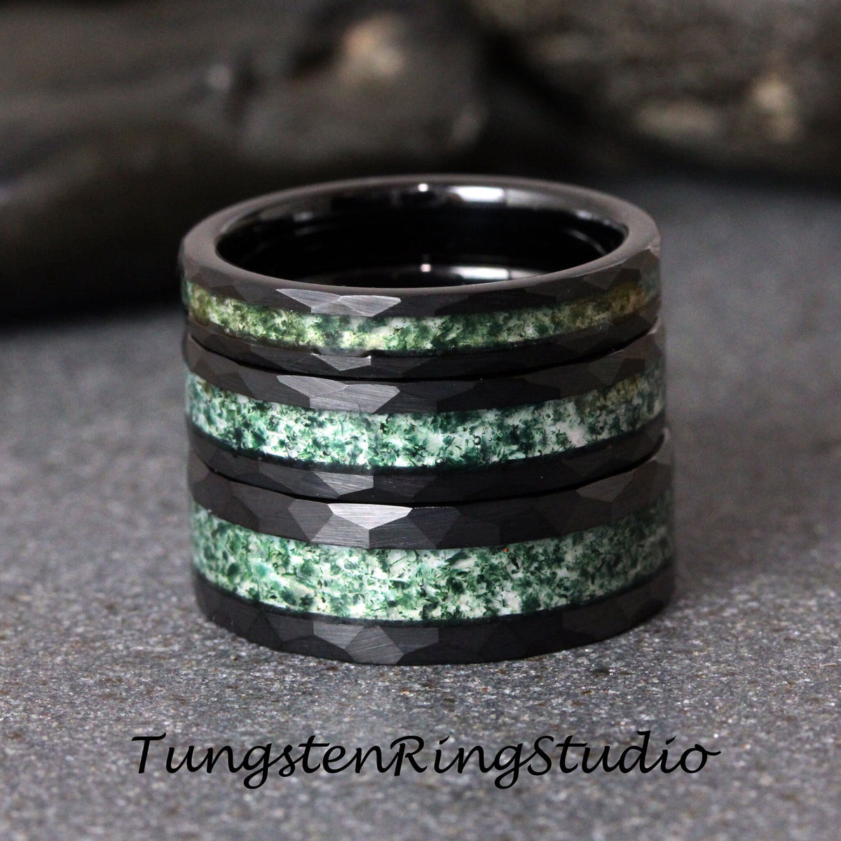 May include: Stack of four black tungsten carbide rings with a green and white inlay. The rings have a faceted, textured finish.